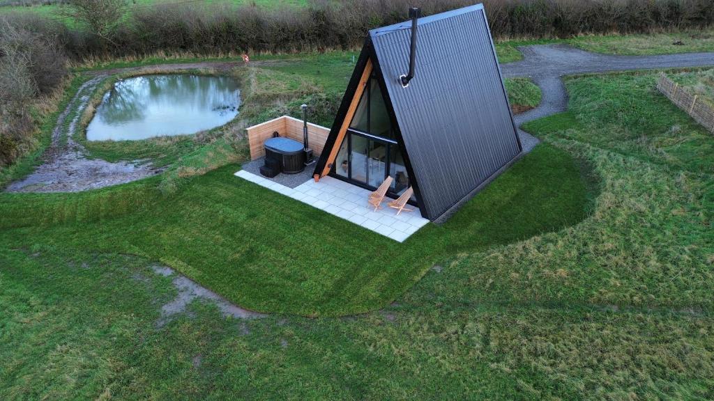 - une vue sur une petite maison avec un étang dans l'établissement Wilder Retreats - A Frame Cabins, à Haverfordwest