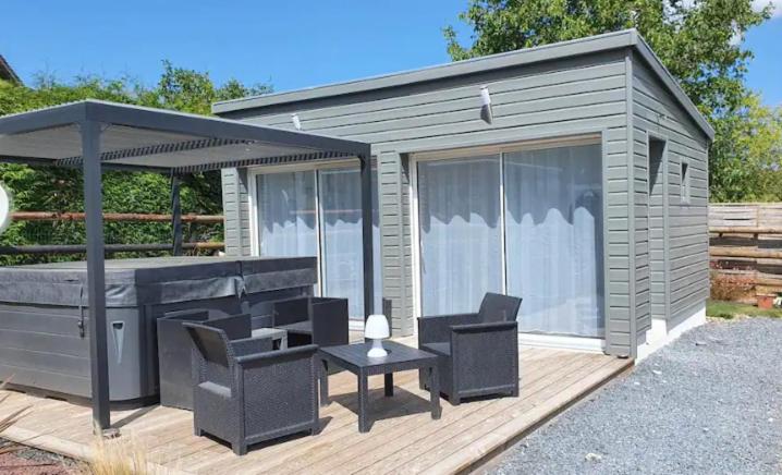 a small cabin with a table and chairs on a deck at Cottage de la mare aux chèvres in Reux