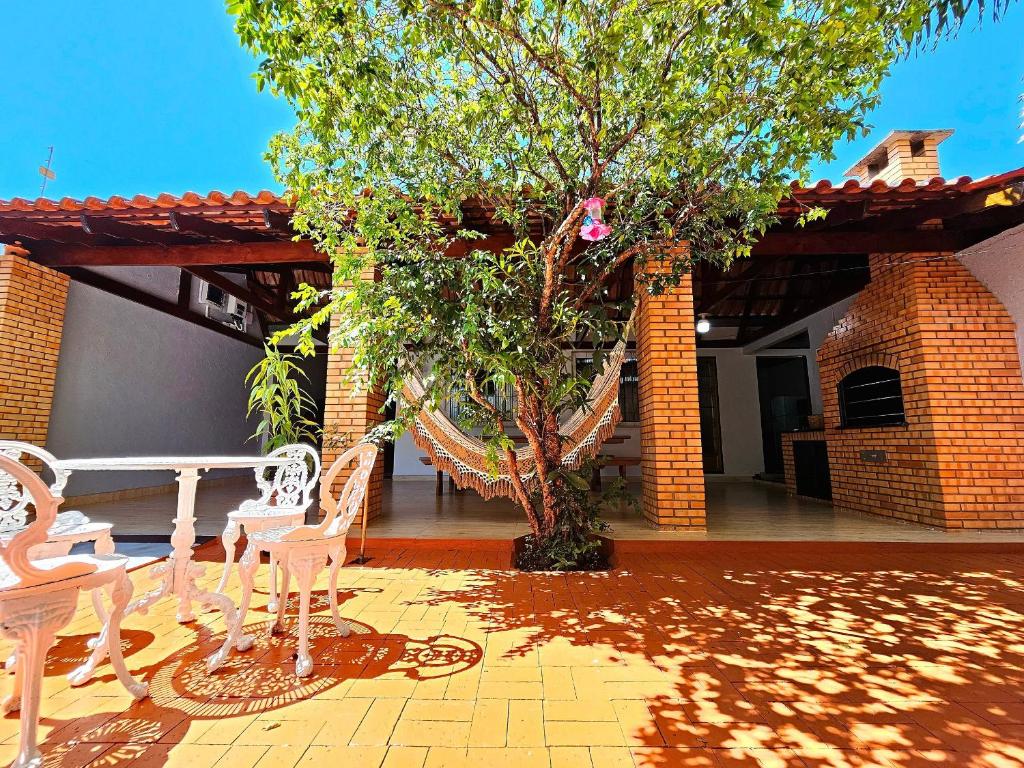 eine Terrasse mit zwei weißen Stühlen und einem Baum in der Unterkunft Linda Edícula com Churrasqueira em casa de Familia in Foz do Iguaçu