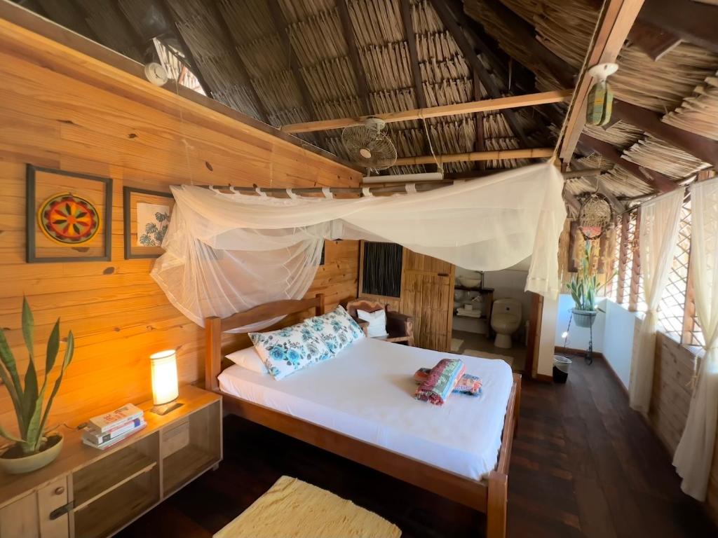 a bedroom with a bed with a mosquito net at Bella Flor Hostel Palomino in Palomino