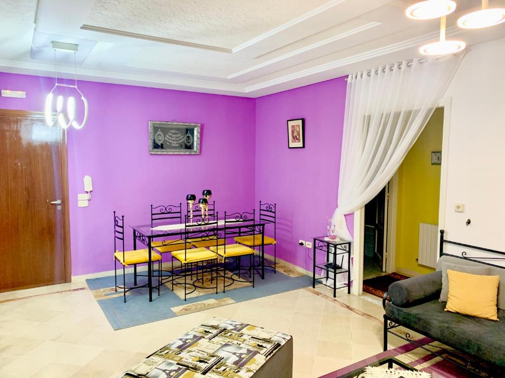 a living room with purple walls and a table with chairs at Dream Appartement El Aouina in Tunis