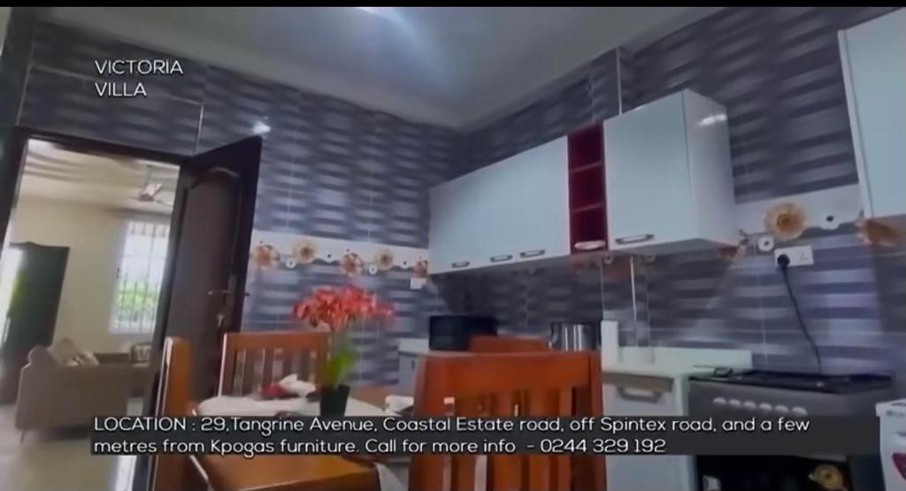 eine Küche mit weißen Schränken sowie einem Tisch und Stühlen in der Unterkunft Victoria Villa in Tema