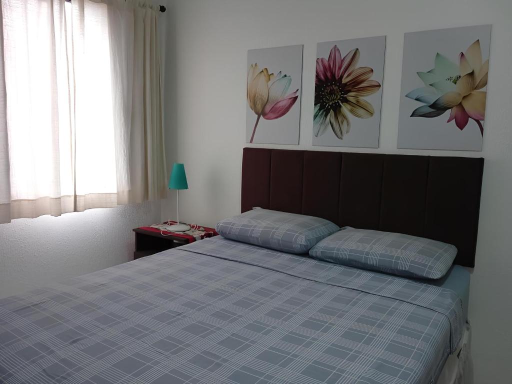 a bedroom with a bed and two pictures on the wall at Apartamento Completo A25 Flat Centro in Mogi das Cruzes