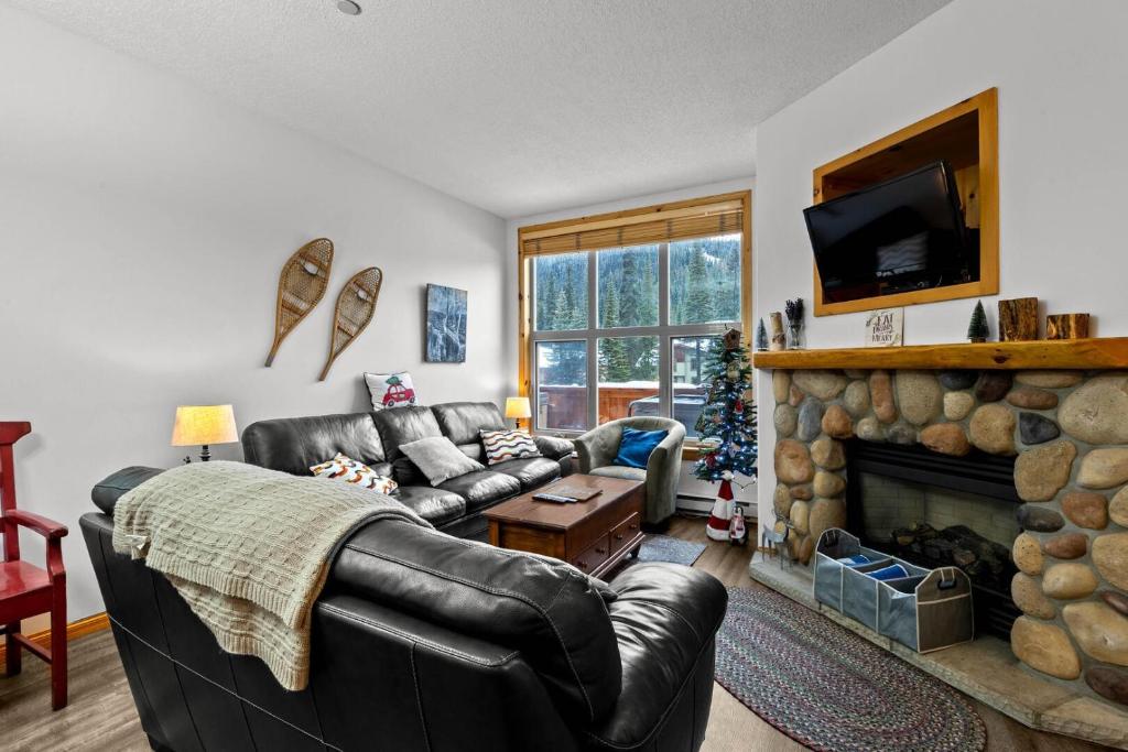 a living room with a leather couch and a fireplace at Crystal Forest #48 By Bear Country in Sun Peaks