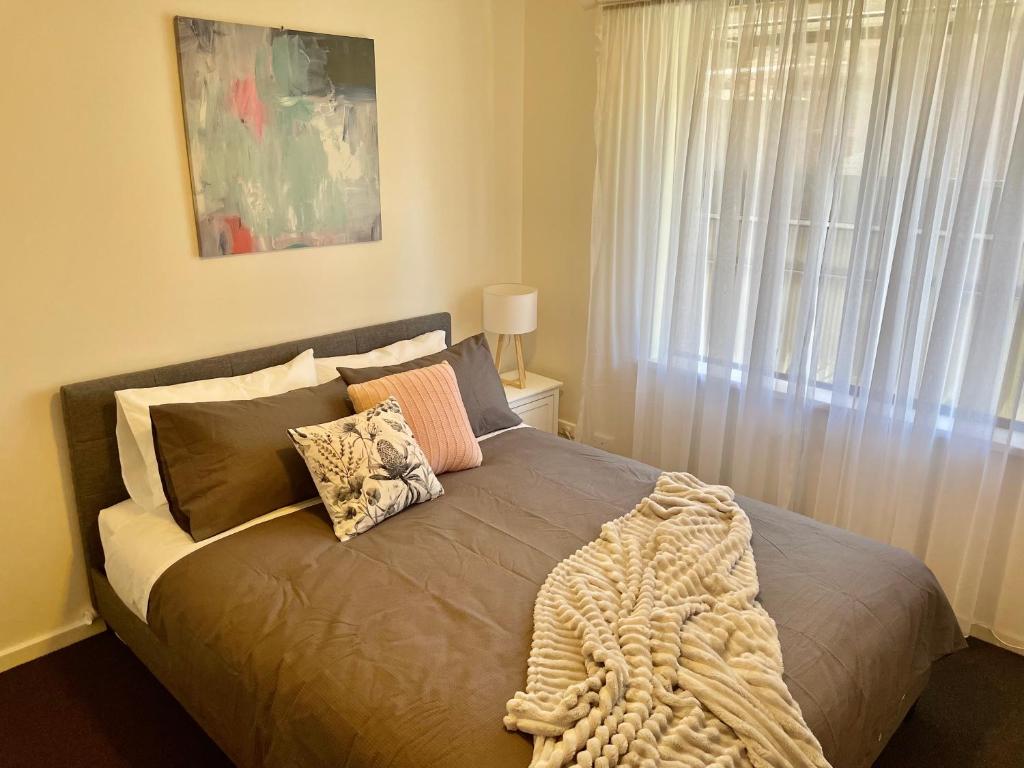 a bed with a blanket on it with a window at Homburg Haven in Tanunda