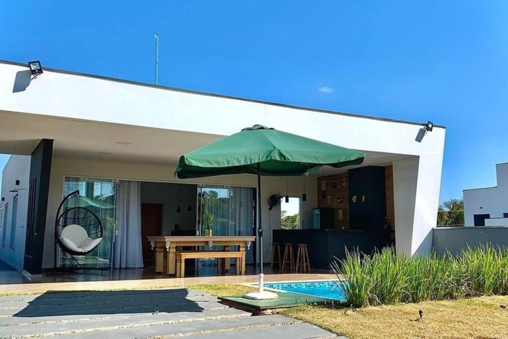 een groene paraplu voor een huis bij Aconchegante casa na represa. in Itaí