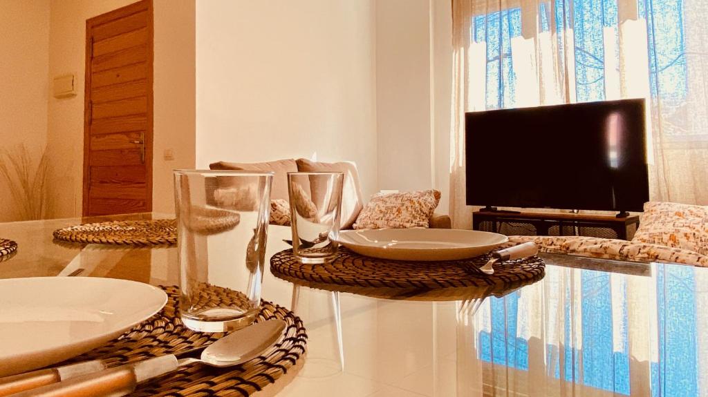 a living room with a table with glasses and a tv at Click&Guest - Alisios House in Las Palmas in Las Palmas de Gran Canaria