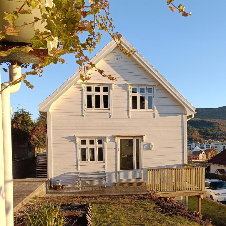 a white house with a porch and a yard at Bellahuset - Charming House in Ulsteinvik in Ulsteinvik