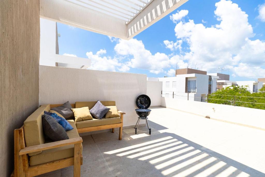 einen Balkon mit einem Sofa auf dem Dach in der Unterkunft Espacio Yuca con Rooftop Privado, Alberca, Parking, Tren Maya cercano in Playa del Carmen