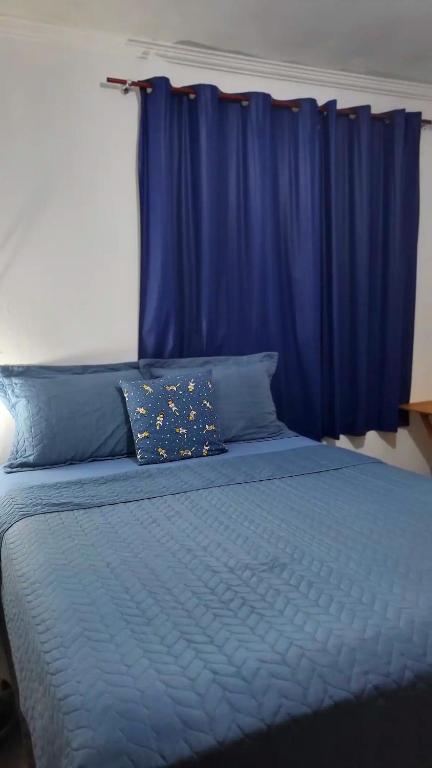 uma cama com lençóis azuis e uma cortina azul em Casa Bangtan em Florianópolis