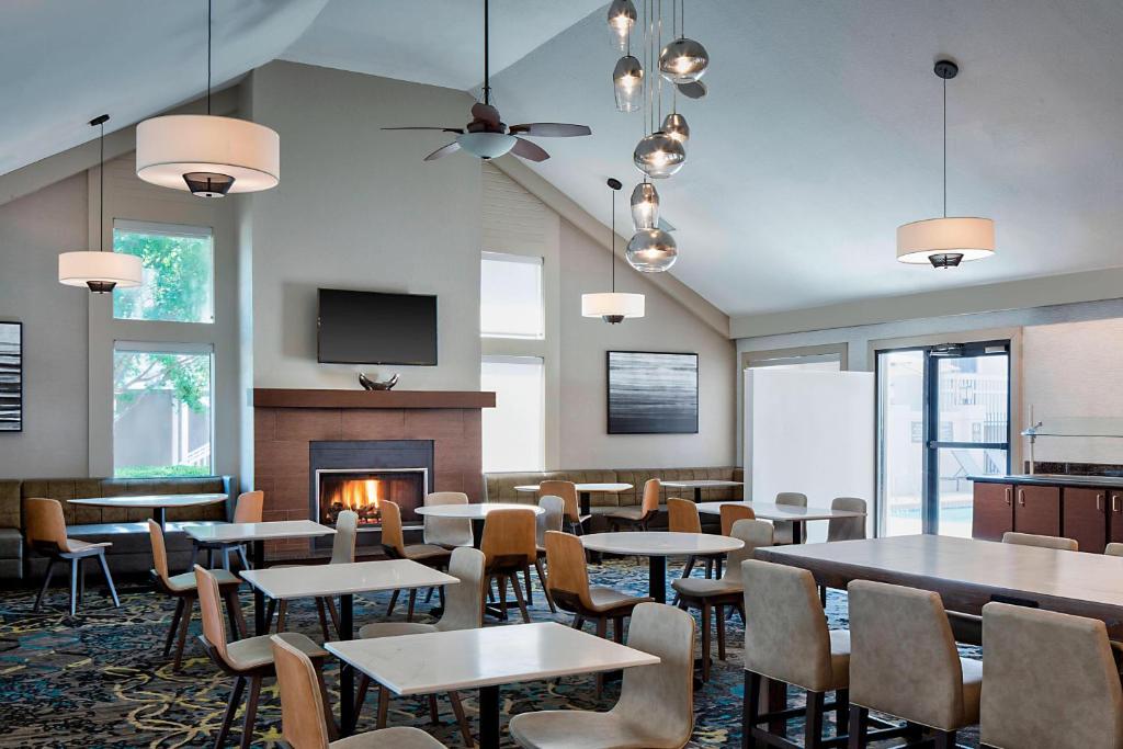 a restaurant with tables and chairs and a fireplace at Residence Inn Dallas Las Colinas in Irving