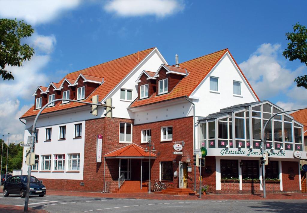 a large white and red building on a street at Hotel Mühleneck in Schortens