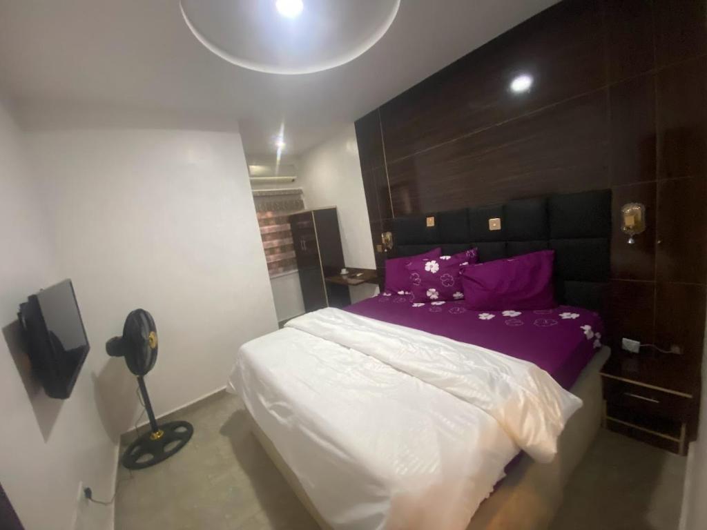 a bedroom with a bed with purple and white sheets at De Emeritus Courtyard in Kubwa