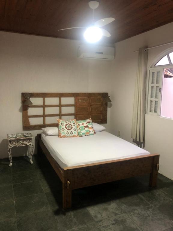 Schlafzimmer mit einem Bett mit einem Kopfteil aus Holz in der Unterkunft Casa de Família com Ar Condicionado, Garagem e Pet friendly in Búzios
