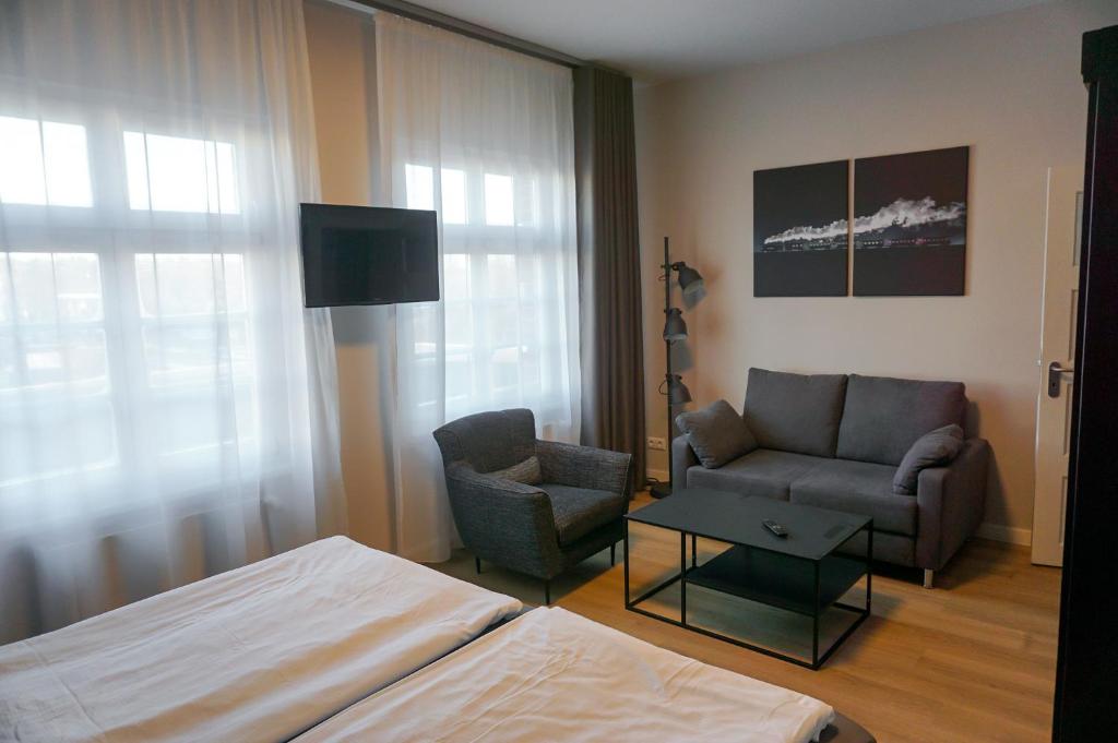 a bedroom with a bed and a couch and a chair at Mollibahnhof - Kühlungsborn West Mollibahnhof West - Ferienwohnung in Kühlungsborn