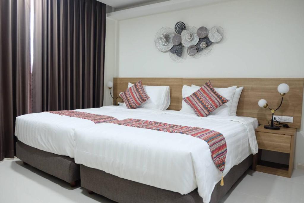 um quarto com uma grande cama branca com almofadas em Christella Hotel Laemchabang em Si Racha