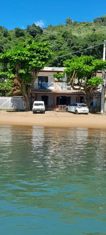 two cars parked in front of a building on the beach at Pousada Pé na Areia in Paraty
