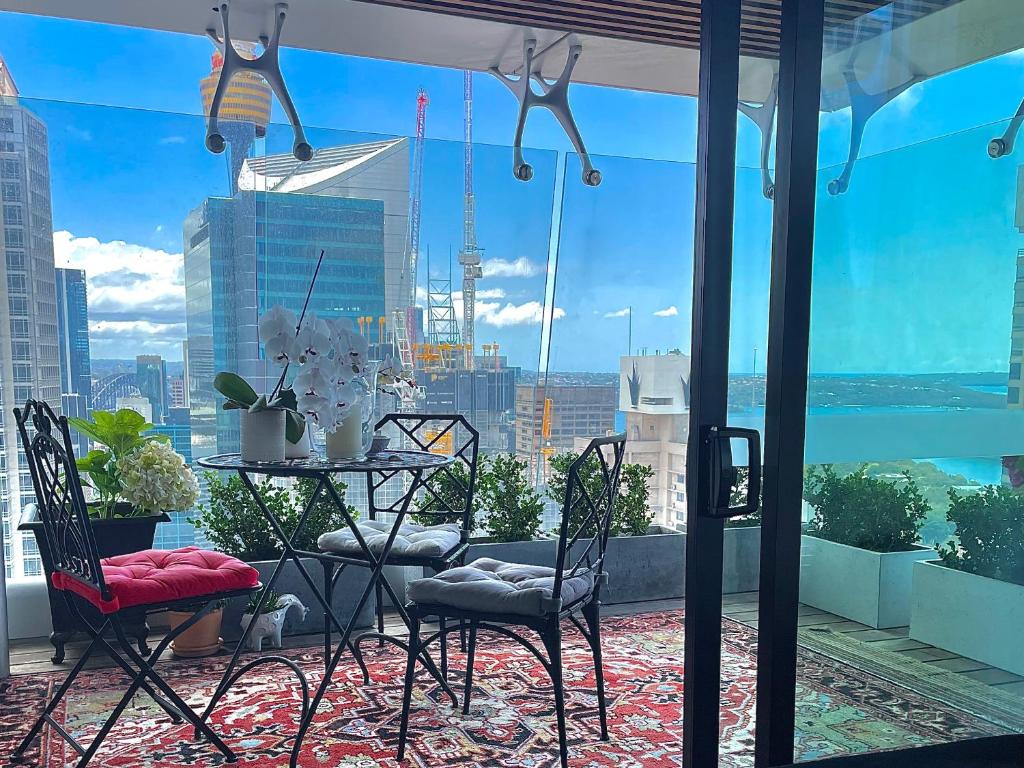 balcón con mesa, sillas y vistas a la ciudad en Sydney Cosmopolitan CBD Apartment en Sídney