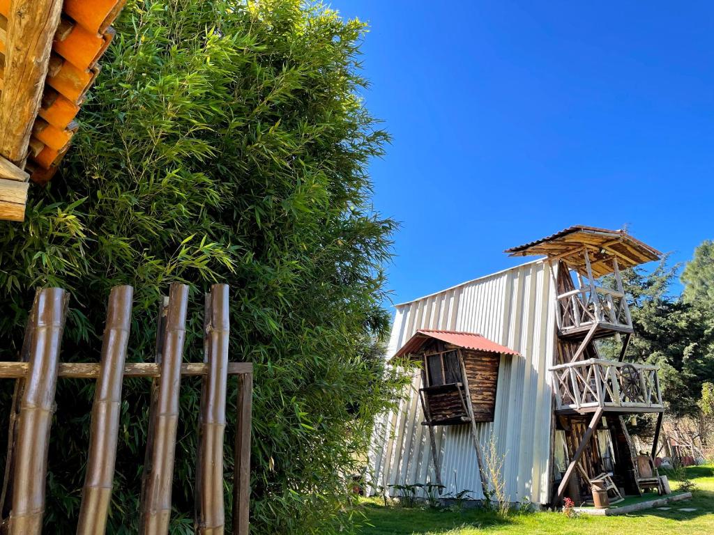 una cerca junto a un árbol al lado de un edificio en Fuego - Wood Cabin Tecpan (No Wifi, Relax), en Tecpán Guatemala