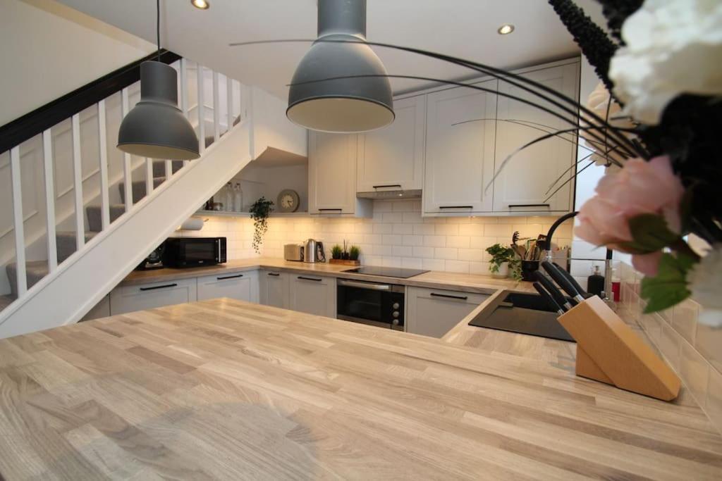 a kitchen with white cabinets and a wooden table at Lovely house overlooking field with woodland walks in Blackwater