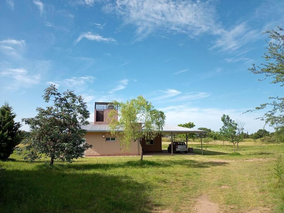 a house with a car parked in a field at Hermosa casa de campo y bosques in Toay