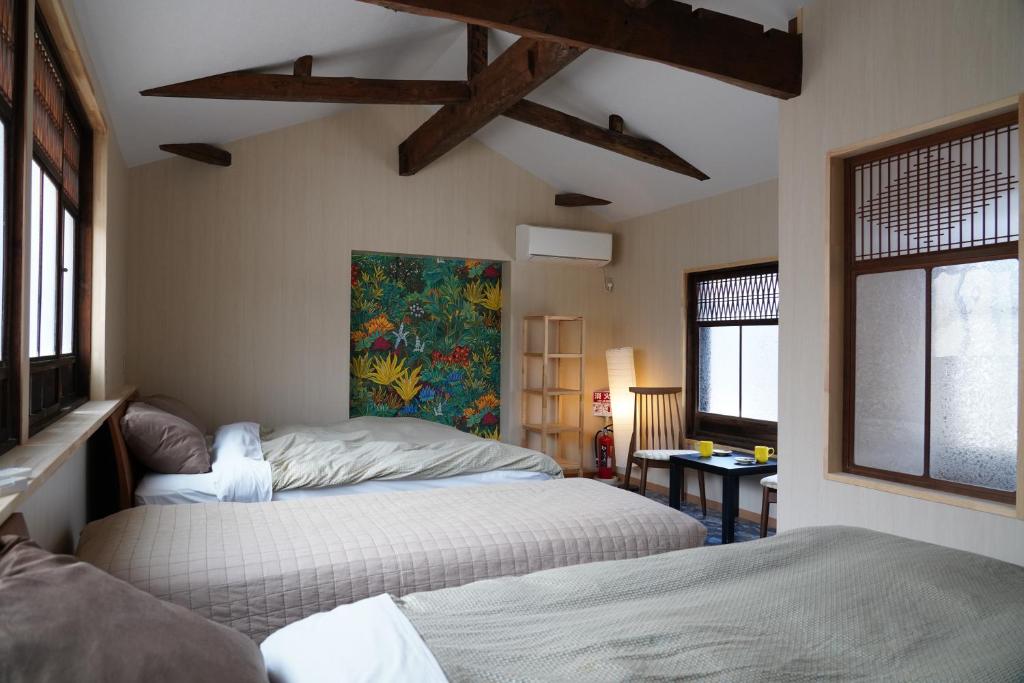 a bedroom with two beds and a painting on the wall at 桜香楽　宮津町家　Sakara Miyazu-Machiya in Miyazu