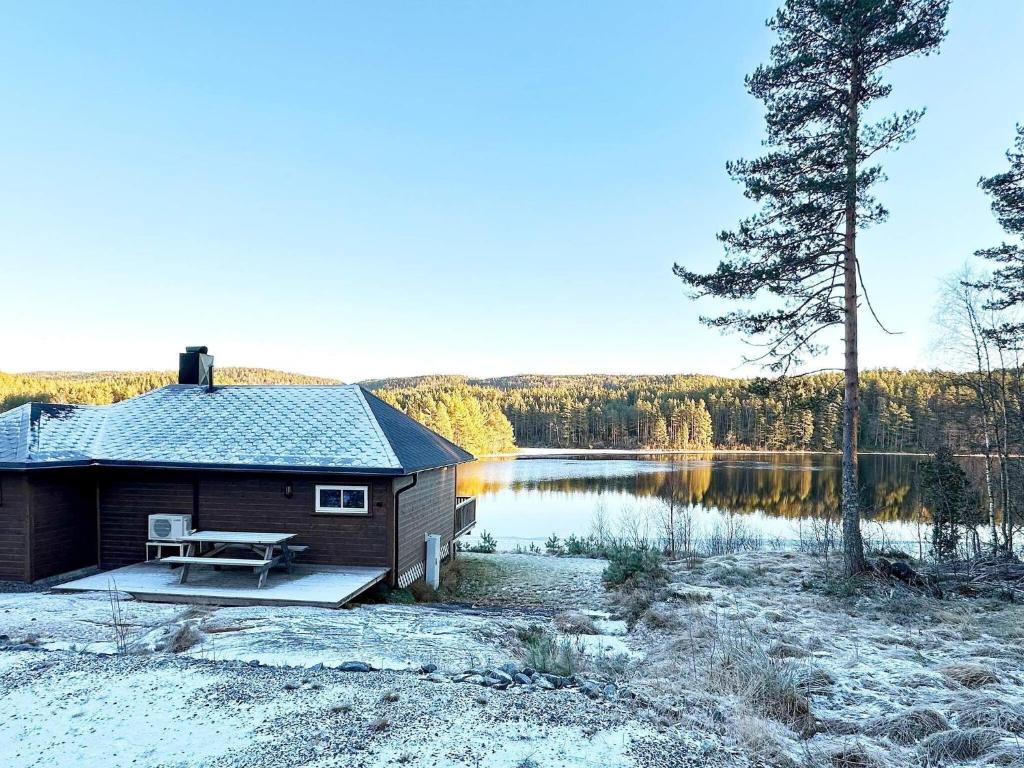 a cabin with a picnic table next to a lake at Holiday home Hornnes in Hornnes