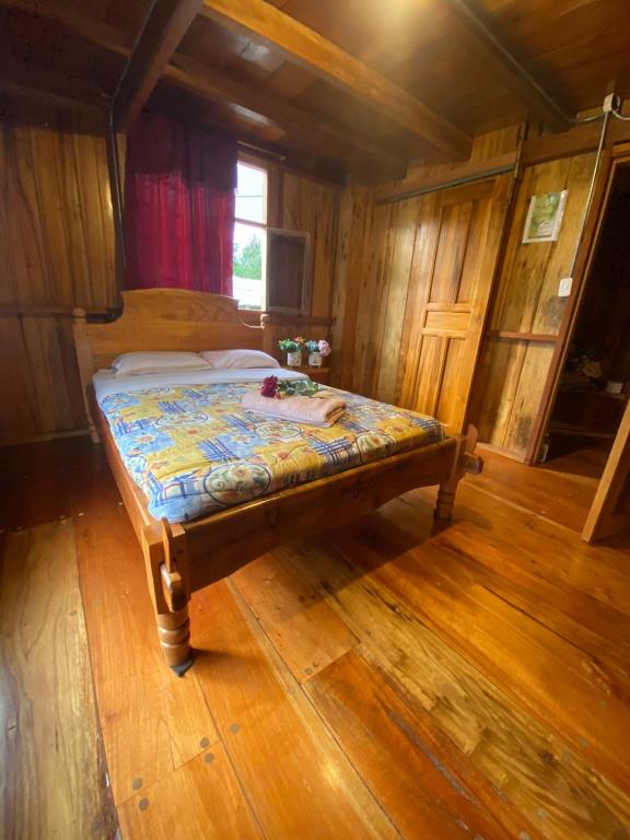 Bett in einem Zimmer mit Holzboden in der Unterkunft Chocotulipe Lodge & Spa in Mindo
