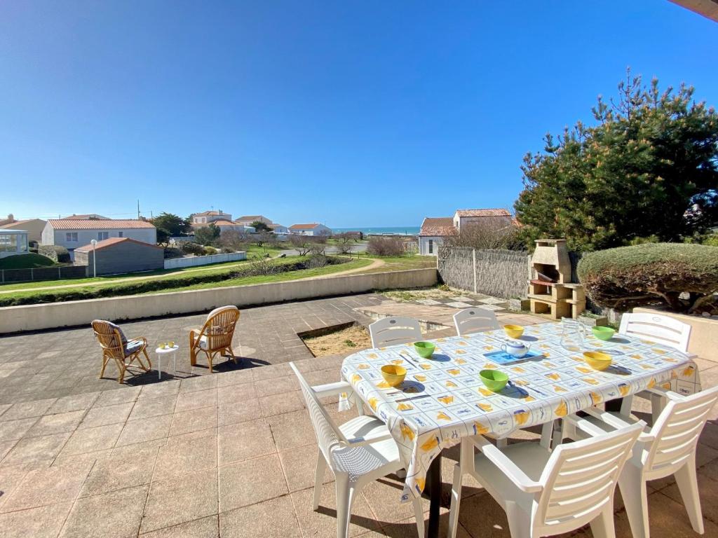 une table blanche et des chaises sur une terrasse dans l'établissement Maison familiale à 400m de la plage avec terrasse de 100m², animaux admis, garage et jardin - FR-1-231-292, à Bretignolles-sur-Mer