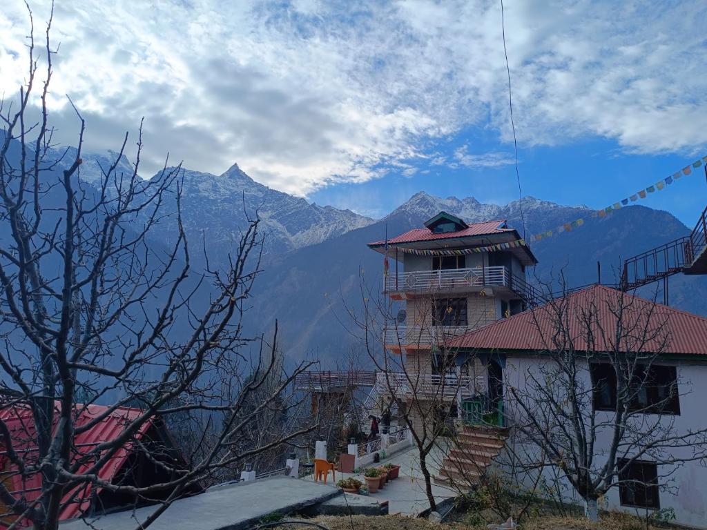 un bâtiment avec une montagne en arrière-plan dans l'établissement Kin Vatika Homestay, à Kalpa