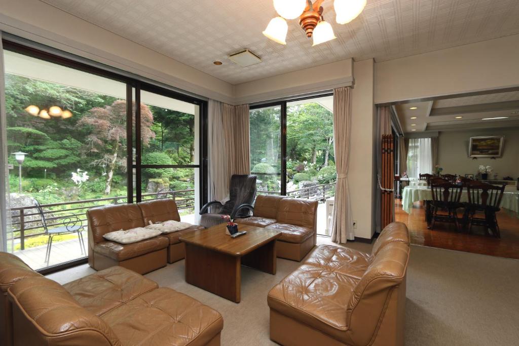 a living room with leather furniture and a large window at Teiensaryo Yamanakako in Yamanakako