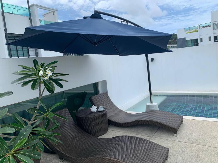 einen blauen Regenschirm auf dem Balkon mit Stühlen in der Unterkunft The Regent Kamala Penthouse with private pool in Kamala Beach