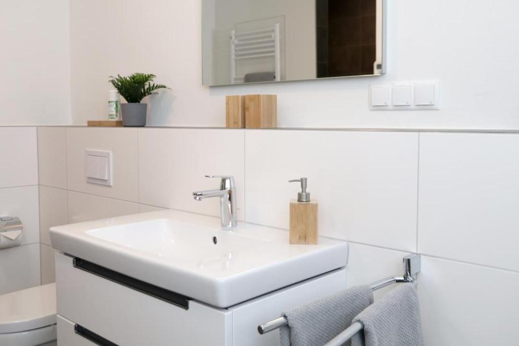 Baño blanco con lavabo y espejo en diemelblick acht - Ferienhaus für 6 Personen mit Sauna, Garten und Dachterrasse mit Panoramablick, en Heringhausen