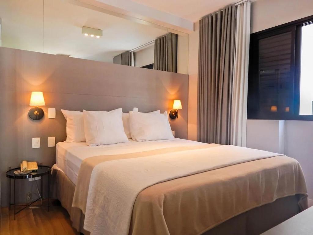 a hotel room with a large bed with white pillows at Easy Star - Flat Aconchegante C/Vaga na Bela Cintra - XA03G in Sao Paulo