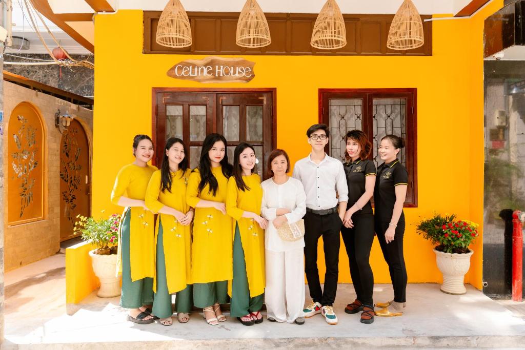 un groupe de personnes debout devant un bâtiment jaune dans l'établissement Celine House, à Hô-Chi-Minh-Ville