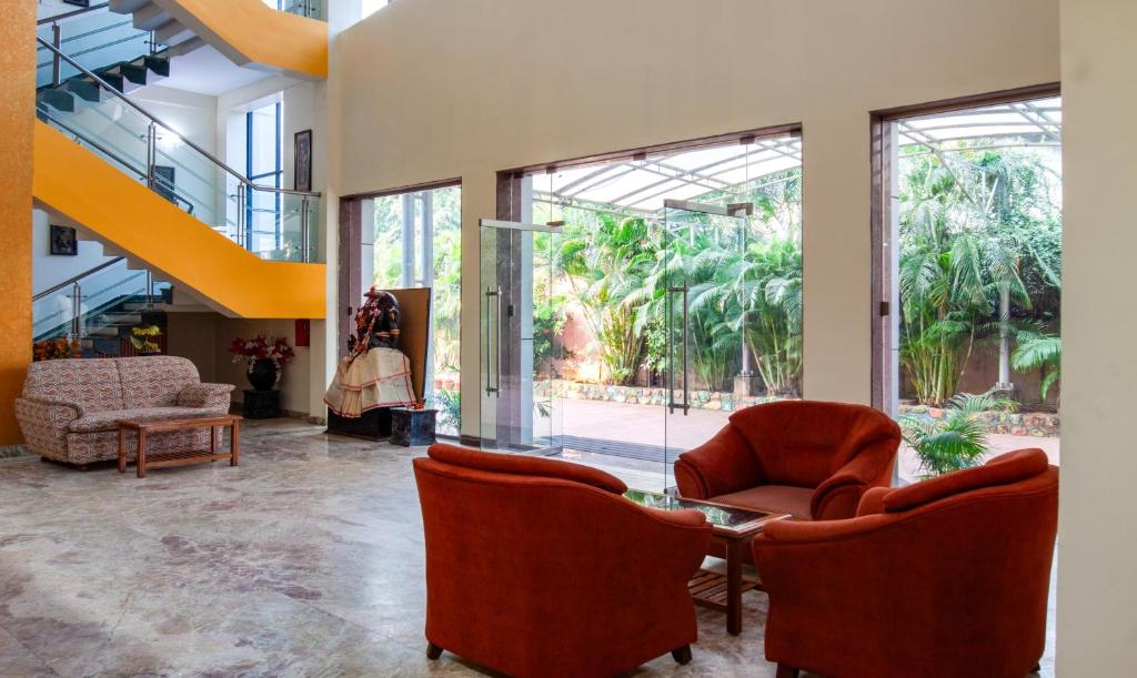 um átrio com duas cadeiras, uma mesa e janelas em Treebo Trend Y Hotels Elite - Jagamara em Bhubaneshwar
