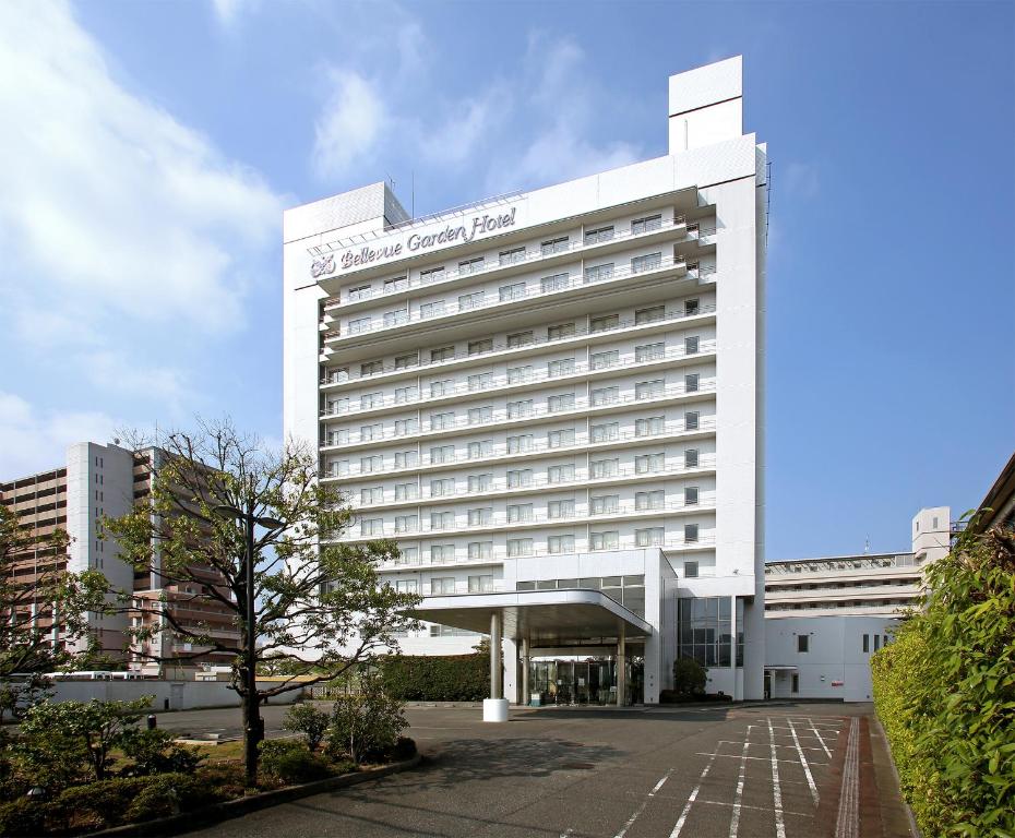 a white hotel building with a tree in front of it at Bellevue Garden Hotel Kansai International Airport in Izumi-Sano