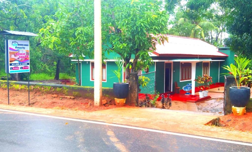 ein grünes Haus mit einem Baum neben einer Straße in der Unterkunft Dambulla Eco Homestay. in Dambulla