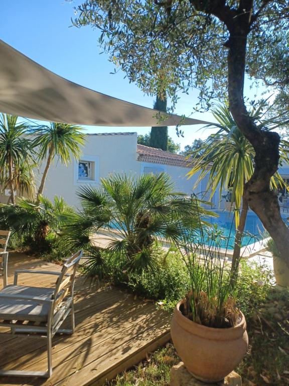 a patio with a table and chairs and palm trees at Le Clos Olives in Comps