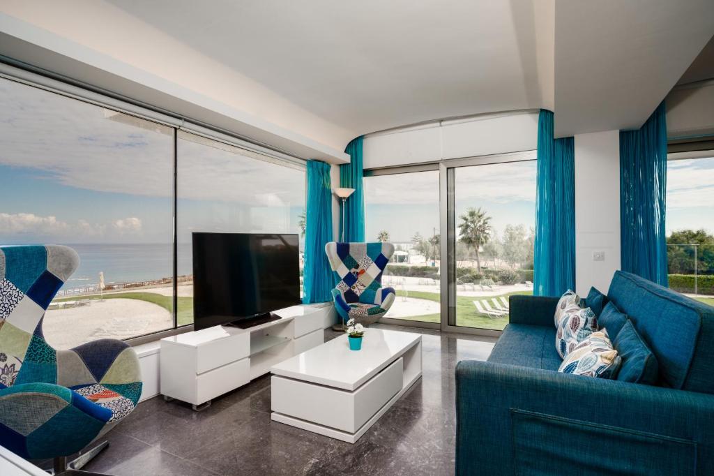 uma sala de estar com mobiliário azul e janelas grandes em Protaras Beachfront Thalassa Suite em Protaras
