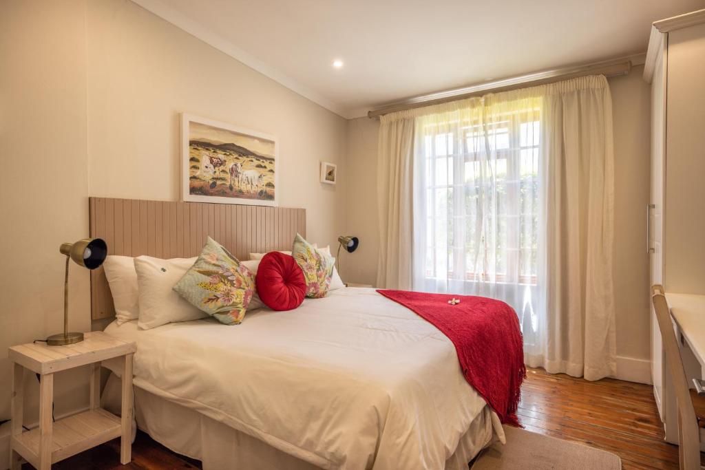um quarto com uma cama com almofadas e uma janela em Lanherne Guest House Bed & Breakfast em Grahamstown