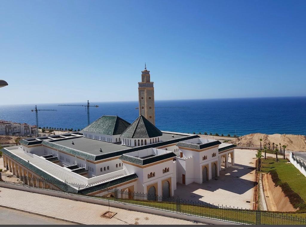 a building with a lighthouse in front of the ocean at Résidence Amina B in Al Hoceïma