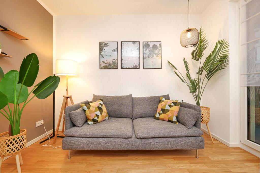 ein Wohnzimmer mit einer Couch und einigen Pflanzen in der Unterkunft Blue Chili 33 - Modernes & gemütliches Business Apartment am Airport BER in Schönefeld