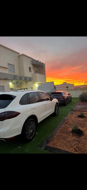 a white car parked in front of a house with the sunset at צימר נחל הבשור in Yeroẖam