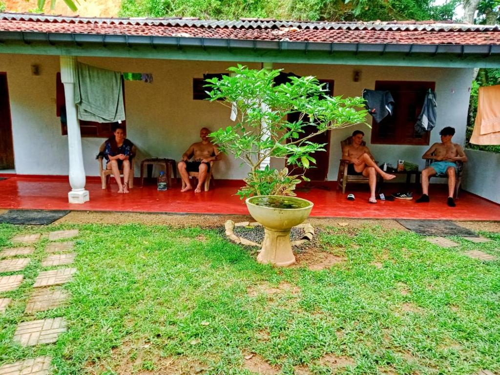 a group of men sitting on the porch of a house at Arachchi Guest House in Mirissa