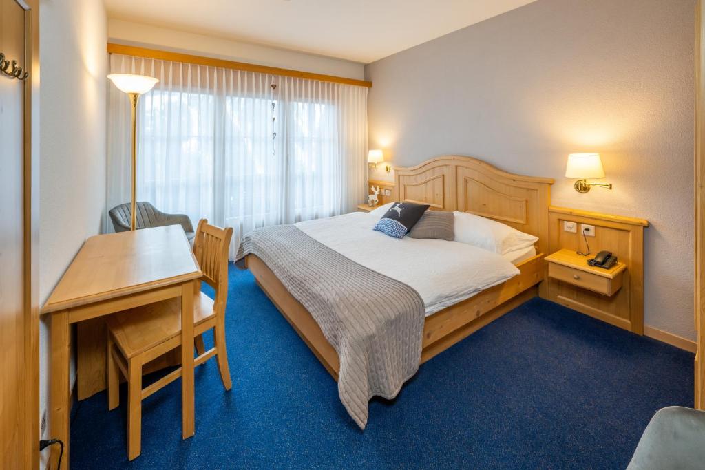 ein Hotelzimmer mit einem Bett, einem Schreibtisch und einem Tisch in der Unterkunft Hotel Bellwald in Bellwald