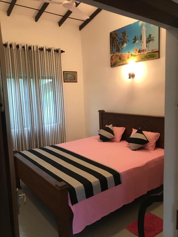 Schlafzimmer mit einem Bett mit rosa Bettwäsche und einem Fenster in der Unterkunft Villa Amorino in Galle