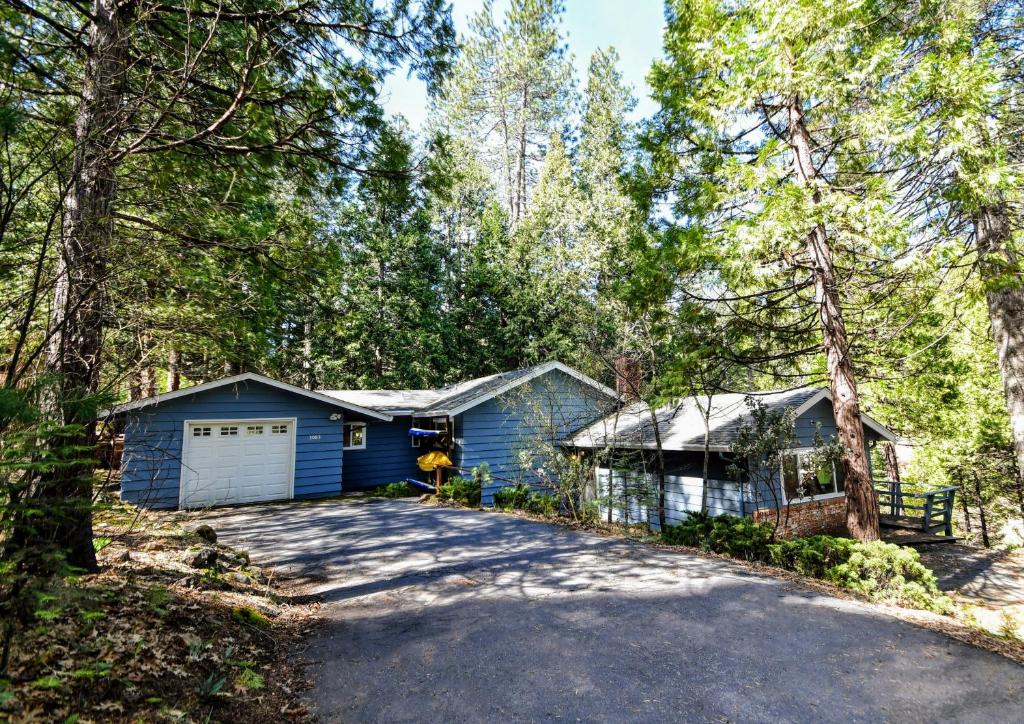 a blue house with a garage in the woods at Casa Cazadores in Arnold