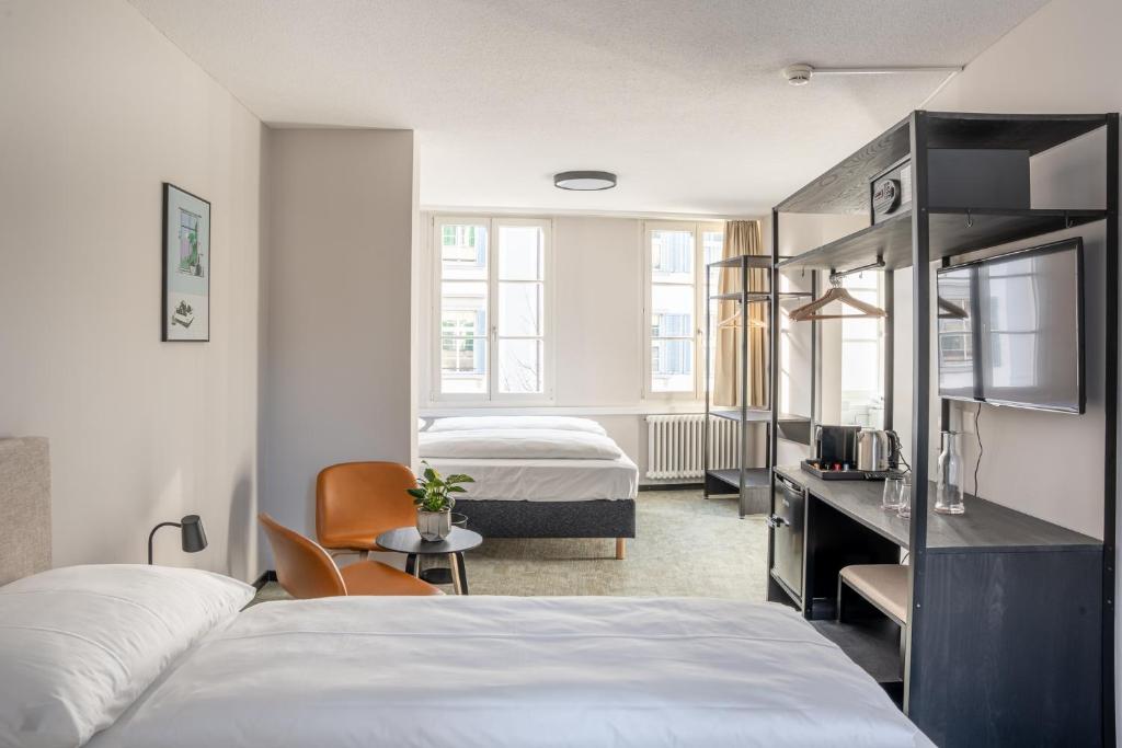 ein Hotelzimmer mit 2 Betten, einem Schreibtisch und einem Schlafzimmer in der Unterkunft Hotel Goldener Stern - contactless check-in in Luzern