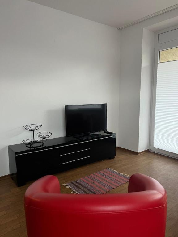 sala de estar con sofá rojo y TV de pantalla plana en AK Ferien-Monteurwohnung, en Olpe